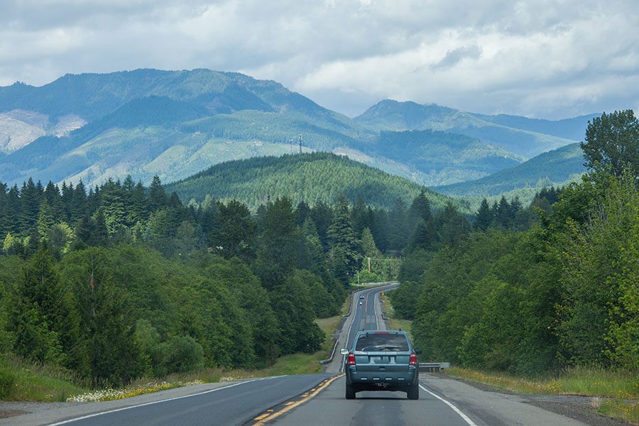 Auto Insurance in Washington - Car Driving on the Highway with Views of the Forest and Mountains