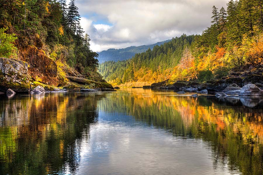 Oregon Cannabis Insurance - View of Colorful Fall Foliage Reflected on the River with Views of the Mountains in the Background in Oregon