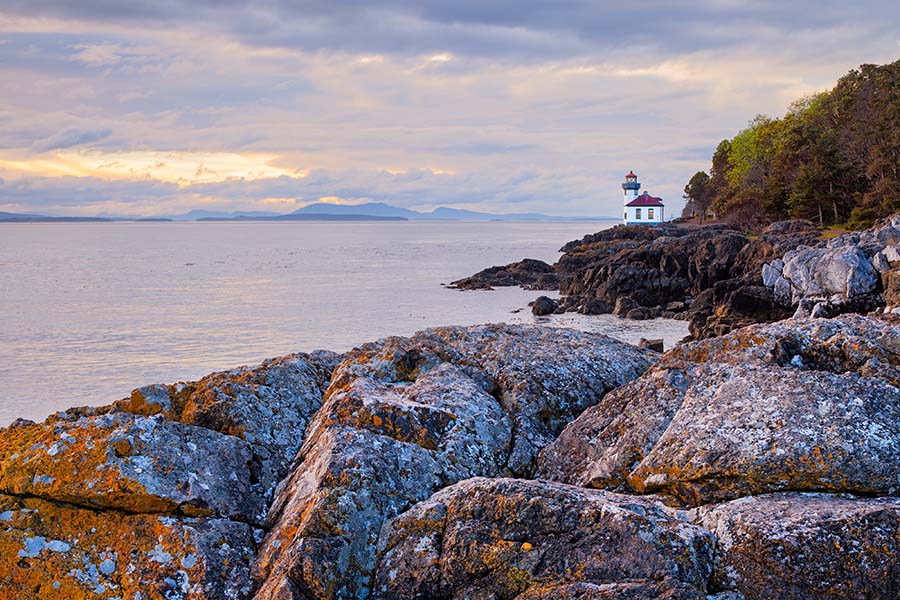 Washington Cannabis Insurance - Lighthouse on the Coast in Washington with Views of Boulders and the Ocean at Sunset