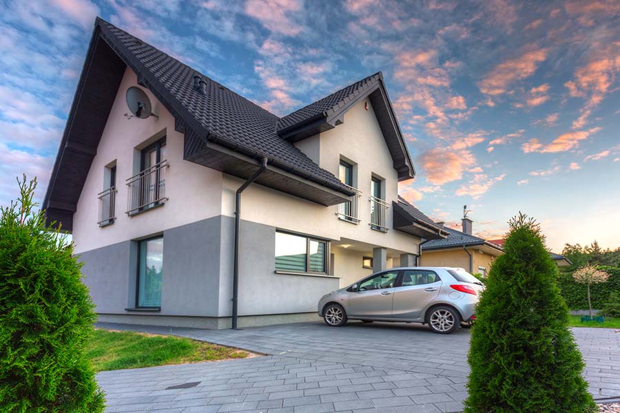Auto and Home Insurance Report Card - View of a Modern Two Story Home with a Car Parked in Front of the House Against a Colorful Sky