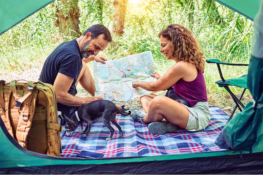 Personal Long Term Care Insurance - Man and Woman Camping Together and Looking At A Map Together With Their Small Dog