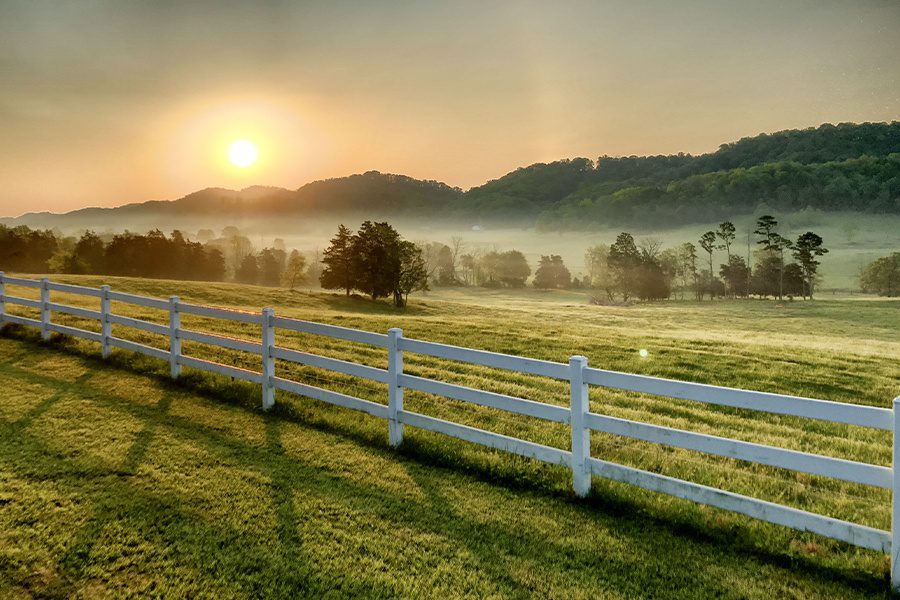 Pasture-Rangeland-Forage-Insurance-Sunrise-Over-Pasture-and-a-White-Fence-with-Trees-and-Hills-in-the-Background