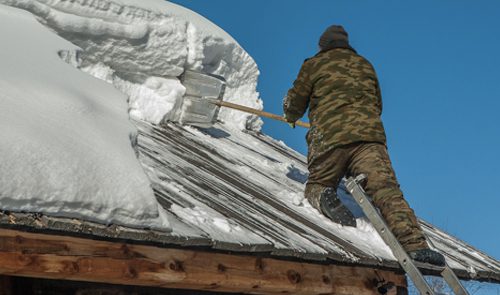 Blog - Man Dressed In Camo On A Ladder Cleaning Snow Off Roof