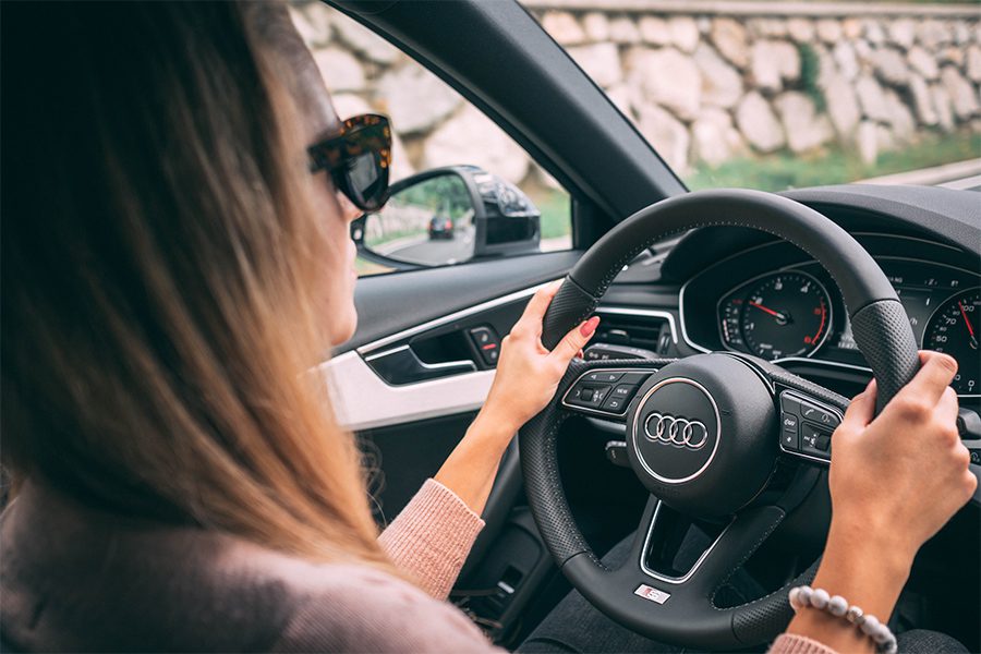 Telematics on Your Insurance Policy - Young Woman Driving in Her Car While Wearing Sunglasses