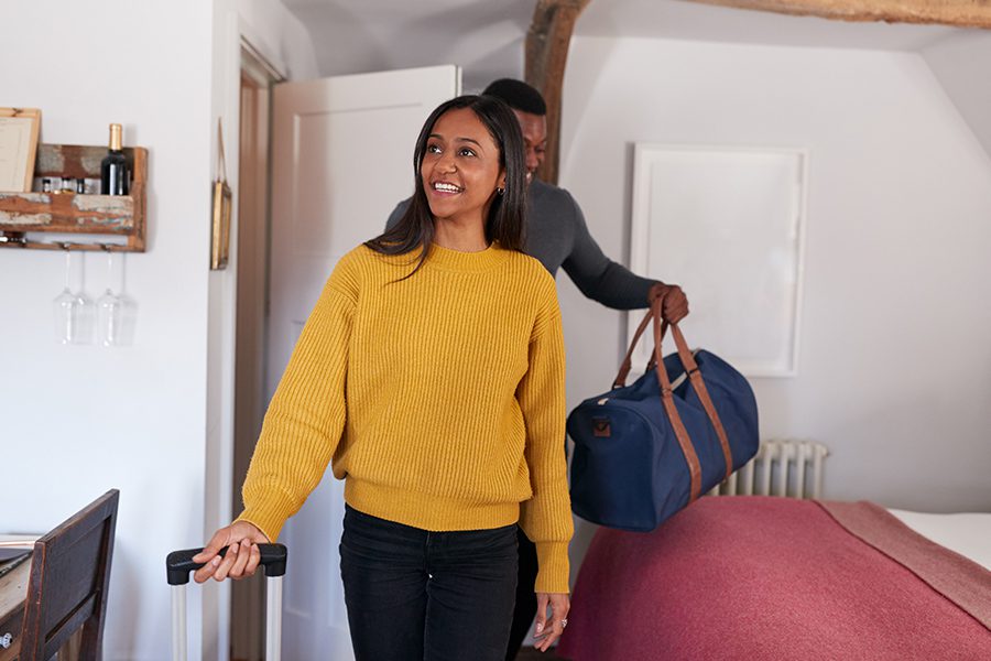 Airbnb Insurance (Home-Sharing Insurance) - Young Couple Walking into the Room of a Rental Home with Luggage