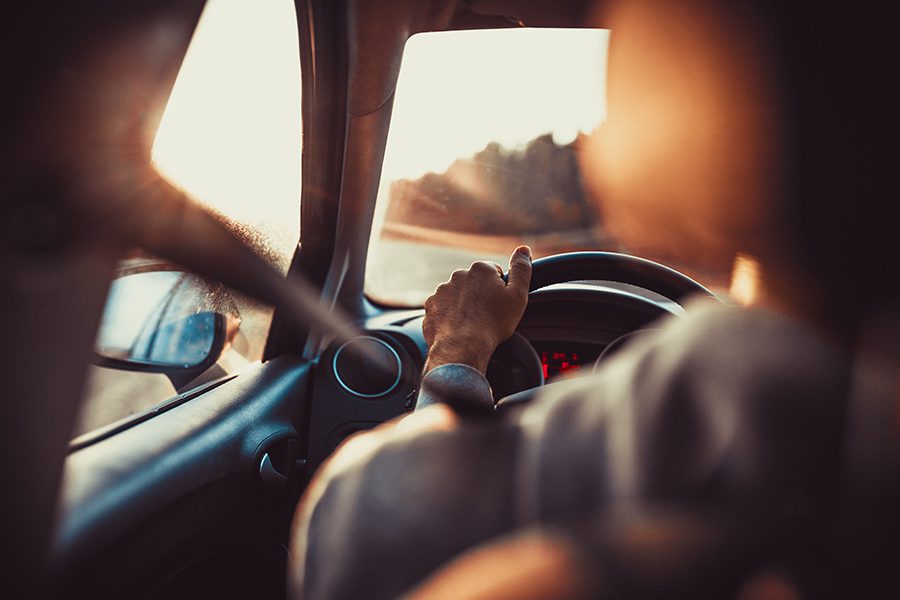 You- “Why Are My Insurance Rates Increasing?” - Close Up of Person Driving a Car Down a Road with Their Seatbelt on at Sunset